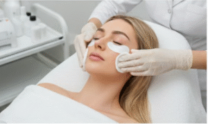Skincare specialist applying soothing cotton pads under a female patient’s eyes as part of post-laser treatment care following a facial rejuvenation procedure in a clean clinical environment.
